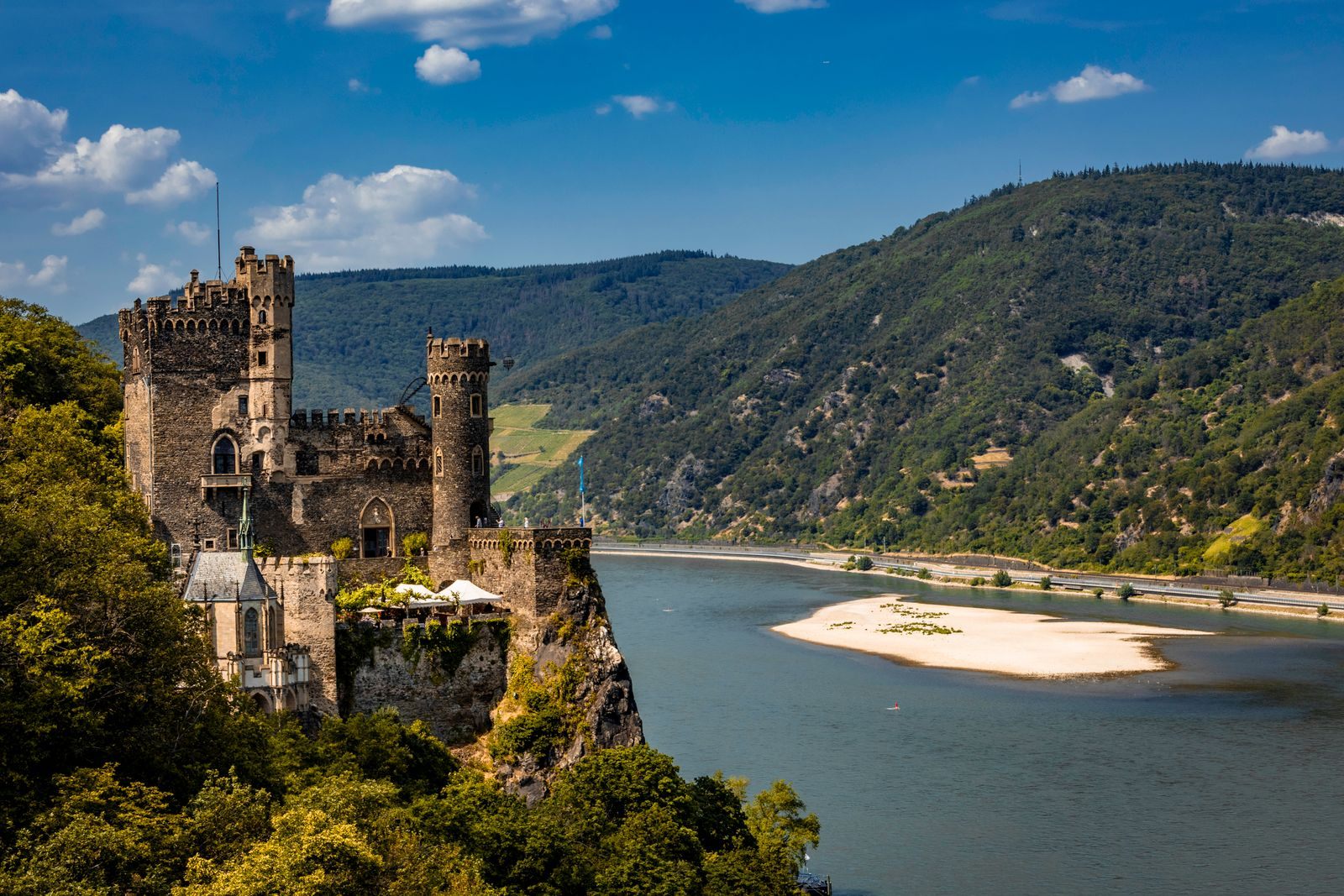 Rheinstein Castle on its crag above the Rhine Gorge with sandbanks in the river, scenery that comes with even the river cruise bargains on the Rhine